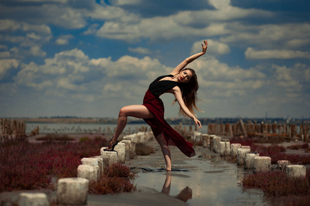 芭蕾舞女演员飞舞在沙子上海滩和天空背景