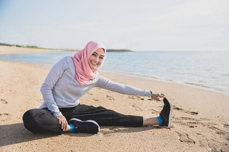 健康运动女人戴盖头微笑着做腿延伸
