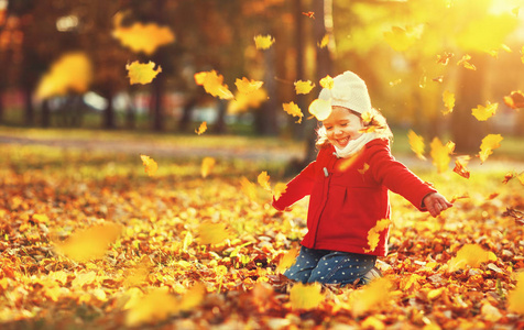 快乐的孩子女孩抛出秋天的落叶和笑