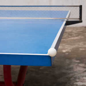 白色的乒乓球球打一个蓝色乒乓球桌的角