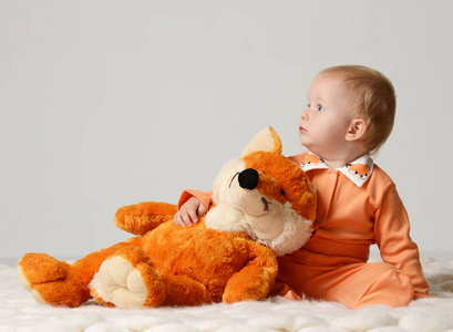 婴儿婴儿孩子蹒跚学步与软狐狸玩具坐，看着角落里