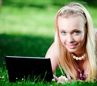 在公园里使用笔记本电脑的年轻女子