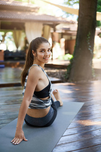 运动女性练习普拉提在和室外瑜伽工作室坐在垫子上。健康的生活方式的概念