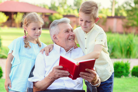 为可爱的孩子们在花园里读书的快乐老祖父