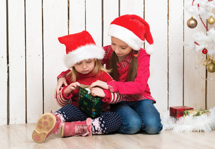 两个小女孩在红色的帽子，坐在地板上用的礼物