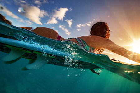 在日落时分在一块板子上划的冲浪女孩