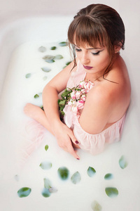 小女孩在沐浴与牛奶和玫瑰色花瓣