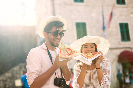 幸福的夫妇的旅游街上吃披萨