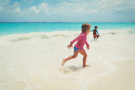 小女孩和男孩跑玩波在海滩上