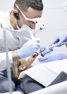 医生牙医对待一个年轻漂亮的女孩病人牙齿。女孩在接待去看牙医。医生牙医治疗牙