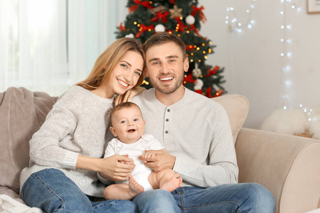 圣诞节快乐父母与婴孩在装饰的屋子里