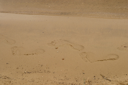 赤脚的脚印在河沿岸的沙滩上图片