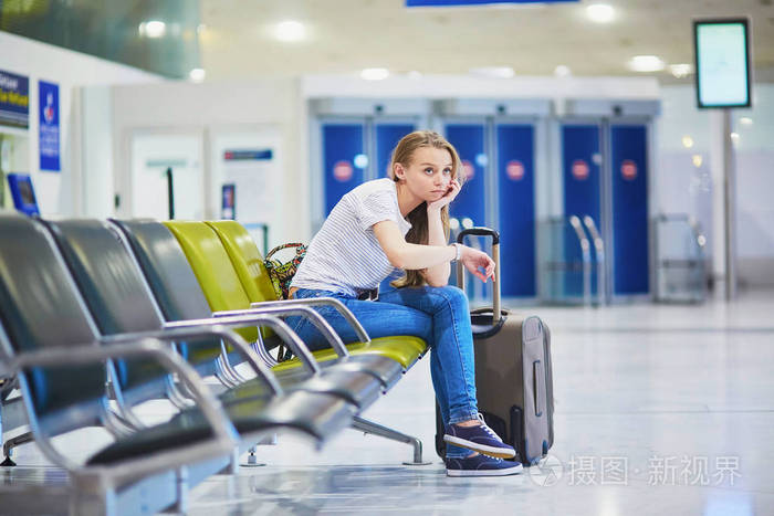 旅游女孩在国际机场等待她的航班看起来神情沮丧