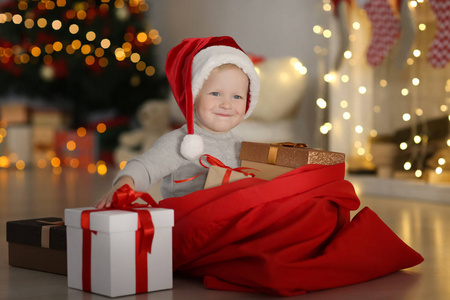 红色的包，与可爱的小男孩，在圣诞老人的帽子，对模糊的圣诞灯