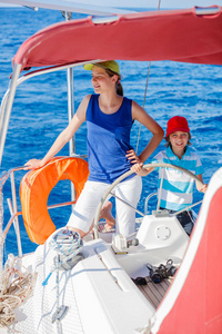 男孩船长和他的姐姐在船上的游艇航行在夏天巡航。冒险旅行，家庭度假游艇与孩子