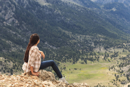 女性旅行者坐的边缘和享受山景
