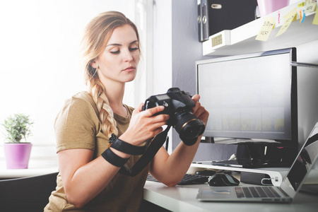 自由摄影师拿照相机在家庭办公室编辑的女人