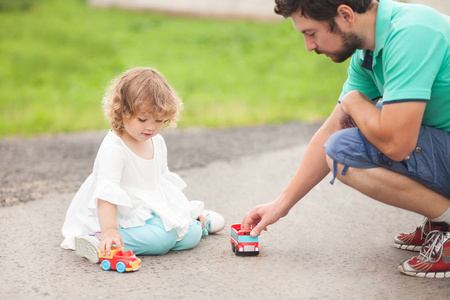 小女孩玩玩具汽车与她的父亲