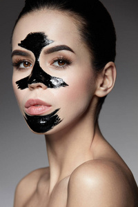 美容化妆品。女性与黑皮肤护理面膜在脸上