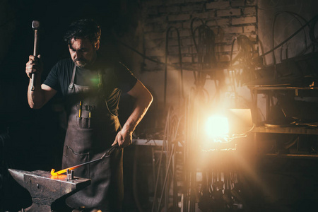 手工锻造用火花烟花的铁匠铺里铁砧上的熔融金属的铁匠