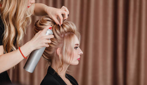 美发师对金发的女商人，在美容院进行晚上的发型特写