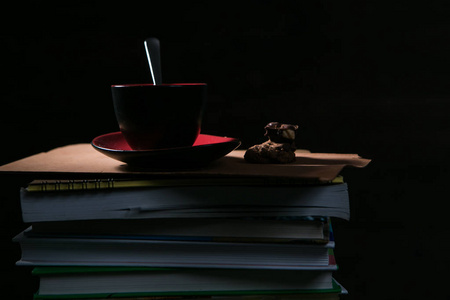 咖啡的杯子和饼干和巧克力在一摞书上