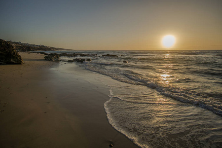 波与水中的石头的海滩上的日出