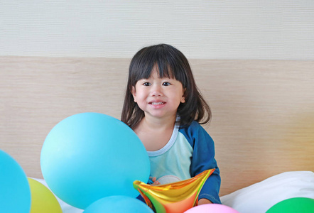 可爱的小亚洲女孩与气球的床上玩