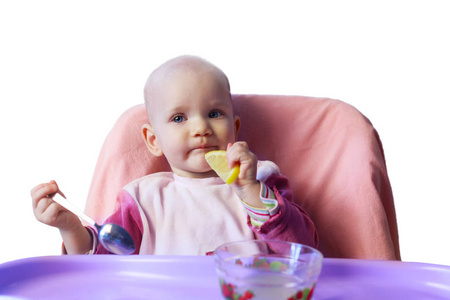 小宝贝女孩吃柠檬孤立在白色背景上的桌子上