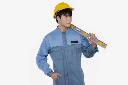 年轻的建筑工人在一个统一的机械师戴黄色安全帽的肖像持有水平
