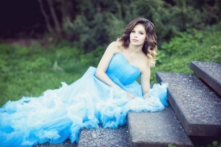 年轻漂亮的女孩，在郁郁葱葱的蓝色连衣裙