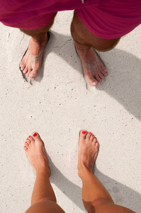 男性和女性的脚站在沙滩上