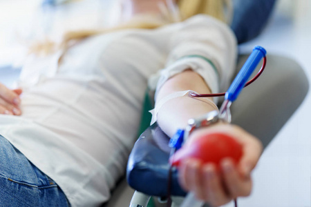 为挽救生命和医学研究的年轻白人女子用手中的玩具心献血