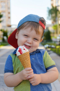 可爱的小男孩抱着蛋卷冰激凌草莓酱