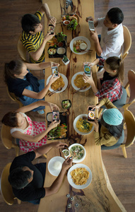享受与朋友和采取手机前合影在餐厅吃午餐晚餐