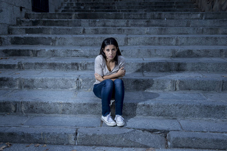 美丽而忧伤的拉美裔女人，绝望和沮丧的坐在城市街道楼梯上