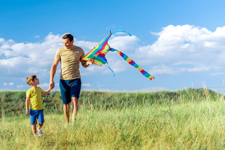 快乐的父亲和儿子玩风筝在自然
