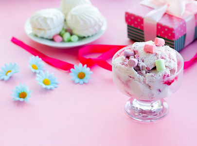 野莓冰淇淋在玻璃甜品碗与礼品 糖果 粉红的底色，选择性焦点模糊背景模糊