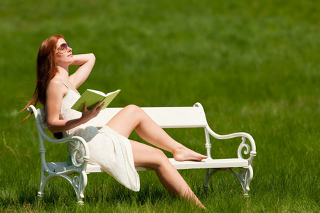红发女人在春天的白凳上看书图片