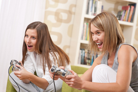 学生两个快乐女性青少年玩电视游戏