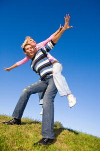 快乐的年轻夫妇，在一片绿色的草地上空跳
