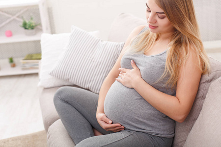 Pegnant 女人爱抚着她的肚子在家里