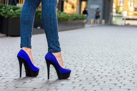 漂亮修长的女性的双腿在紧身牛仔裤和蓝色的鞋子上