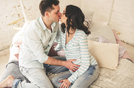 幸福的家庭的怀孕妇女和年轻丈夫亲吻