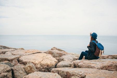 旅行者的女孩与一个背包在海边戴着帽子。旅游，休闲，徒步旅行