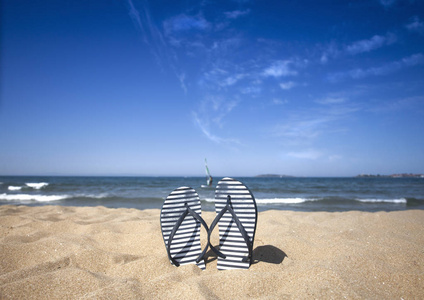蓝色的凉鞋翻转在沙滩上, 蓝色的海和天空背景在夏季的假期。复制空间