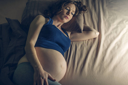 怀孕的女人在夜里躺在床上感到疼痛, 晚上失眠。怀孕和健康的概念