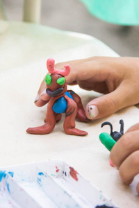 孩子玩五颜六色的粘土制作动物的数字。手特写