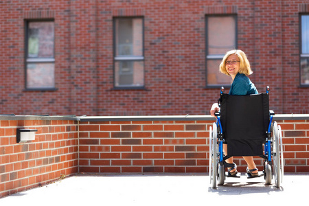 幸福的女人，对砖砌建筑包围的轮椅