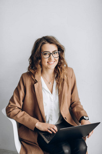 微笑美丽的商界妇女在办公室的一个白色的墙上的笔记本电脑眼镜